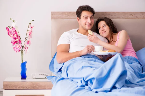 Lycklig familj som äter frukost på sängen — Stockfoto