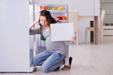 Hamile kadın buzdolabının yanında boş mesajla bekliyor.