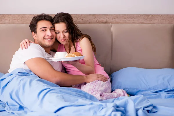 Lycklig familj som äter frukost på sängen — Stockfoto