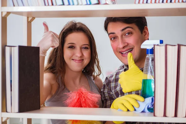 Esposa y marido limpiando polvo de la estantería — Foto de Stock