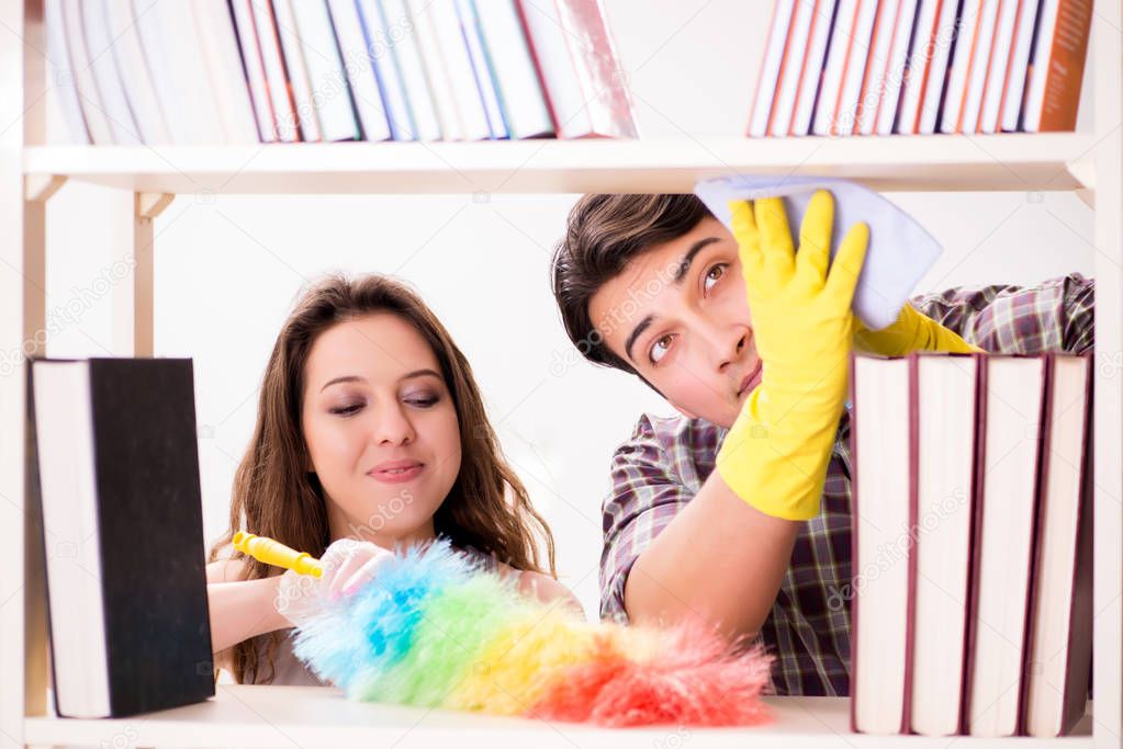 Wife and husband cleaning dust from bookshelf