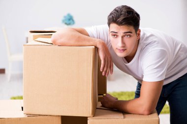 Genç adam evde kutuları taşıyor.
