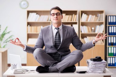 Genç işadamı ofiste meditasyon yapıyor.