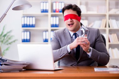 Ofiste masasında oturan gözü bağlı iş adamı.