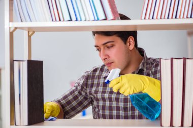 Kitaplıktaki tozları temizleyen adam