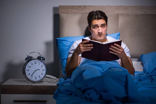 Jovem homem lendo livro na cama — Fotografia de Stock