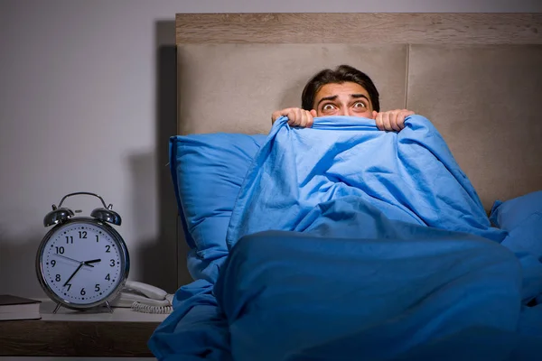 Young man scared in bed — Stock Photo, Image