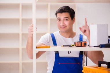 İşçi adam montaj kitaplığını tamir ediyor