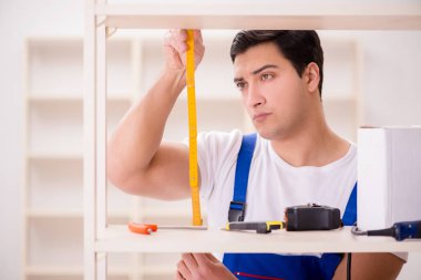 İşçi adam montaj kitaplığını tamir ediyor