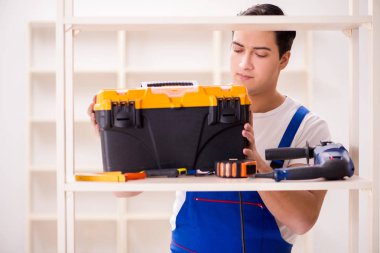 İşçi adam montaj kitaplığını tamir ediyor