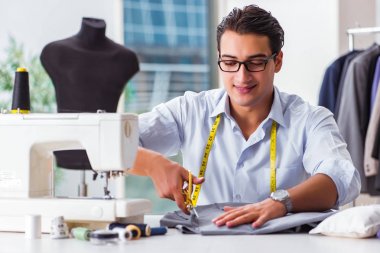 Genç terzi yeni elbiseler üzerinde çalışıyor.