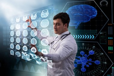 Erkek doktor MRI taramasının röntgenini çekiyor.