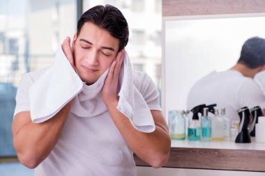 Genç yakışıklı adam yüz kremi sürüyor.