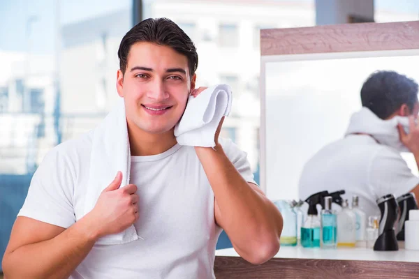 Joven hombre guapo aplicando crema facial — Foto de Stock