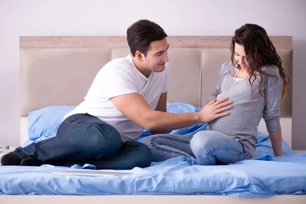 Família jovem com esposa grávida esperando bebê na cama — Fotografia de Stock