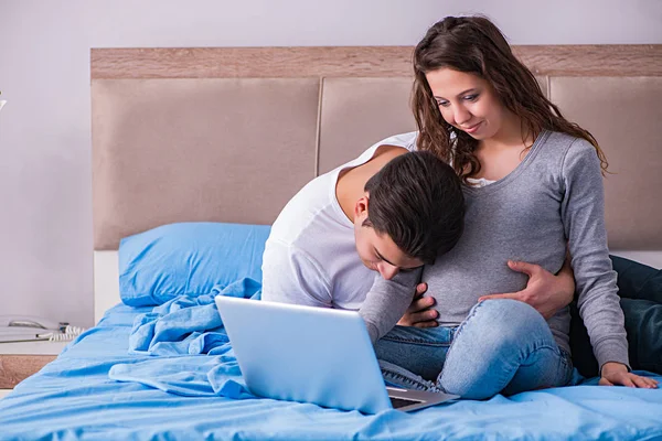 Familia joven con esposa embarazada esperando al bebé en la cama —  Fotos de Stock