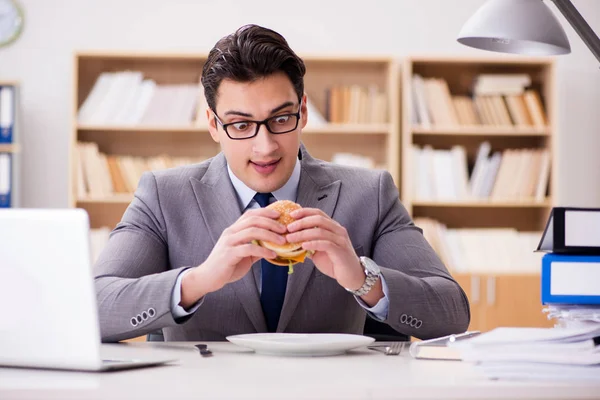 Hambriento empresario divertido comer sándwich de comida chatarra — Foto de Stock