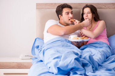 Mutlu bir aile yatakta kahvaltı yapıyor.