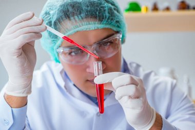 Laboratuvar hastanesinde kan testi üzerinde çalışan genç bir doktor.