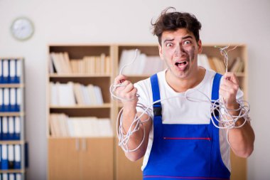 Kablolara dolanmış komik genç elektrikçi.