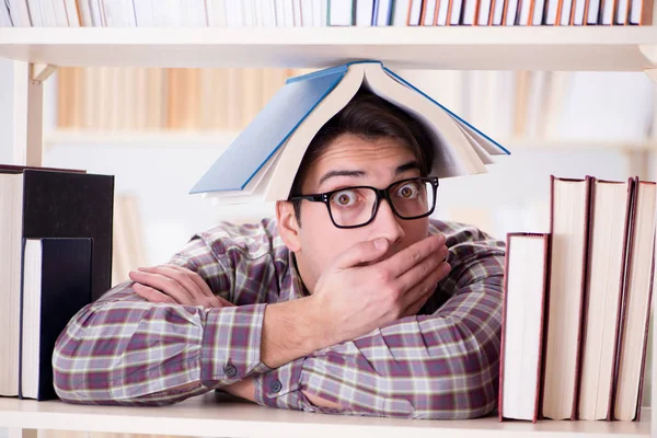 Giovane studente in cerca di libri nella biblioteca del college — Foto Stock