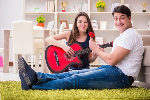 Pareja romántica tocando la guitarra en el suelo — Foto de Stock