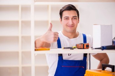 İşçi adam montaj kitaplığını tamir ediyor