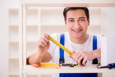 İşçi adam montaj kitaplığını tamir ediyor