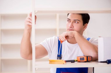 İşçi adam montaj kitaplığını tamir ediyor