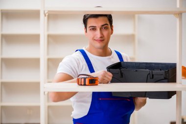 İşçi adam montaj kitaplığını tamir ediyor