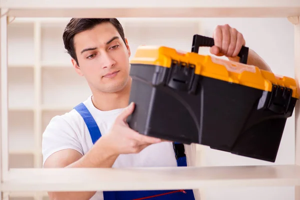 Trabalhador reparando montagem estante de livros — Fotografia de Stock