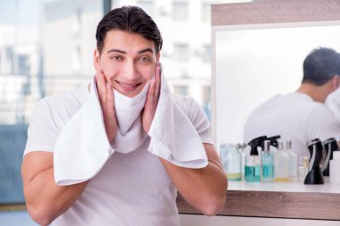 Genç yakışıklı adam yüz kremi sürüyor.