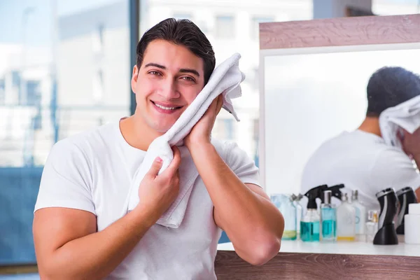 Joven hombre guapo aplicando crema facial — Foto de Stock