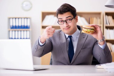 Aç komik iş adamı abur cubur sandviç yiyor.