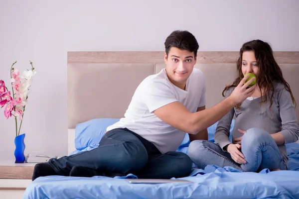 Jeune famille avec femme enceinte qui attend bébé au lit — Photo