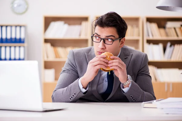 Hambriento empresario divertido comer sándwich de comida chatarra — Foto de Stock