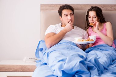 Mutlu bir aile yatakta kahvaltı yapıyor.