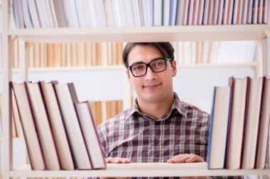 Üniversite kütüphanesinde kitap arayan genç bir öğrenci.