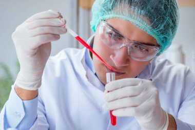 Laboratuvar hastanesinde kan testi üzerinde çalışan genç bir doktor.