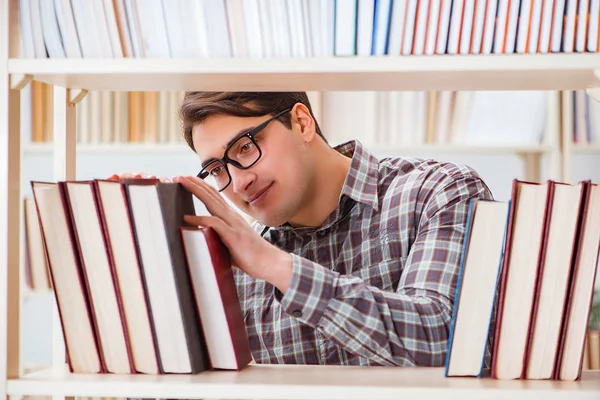 Jonge student op zoek naar boeken in universiteitsbibliotheek — Stockfoto