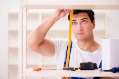 İşçi adam montaj kitaplığını tamir ediyor