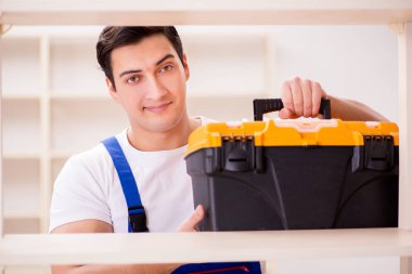 İşçi adam montaj kitaplığını tamir ediyor