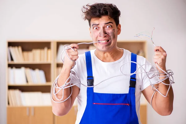 Смешной человек, делающий ремонт электропроводки дома — стоковое фото