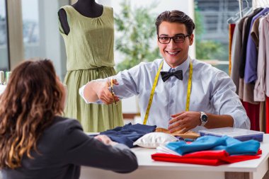 Bayan müşteriyle çalışan genç bir terzi.