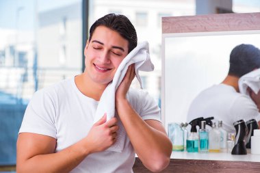 Genç yakışıklı adam yüz kremi sürüyor.