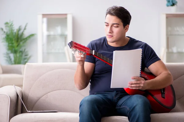 Ung man övar gitarr hemma — Stockfoto