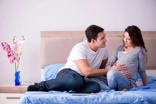 Familia joven con esposa embarazada esperando al bebé en la cama —  Fotos de Stock