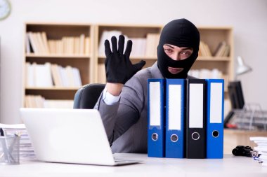 Suçlu iş adamı ofiste kar maskesi giyiyor.