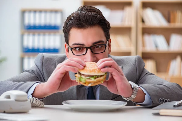 Hambriento empresario divertido comer sándwich de comida chatarra — Foto de Stock