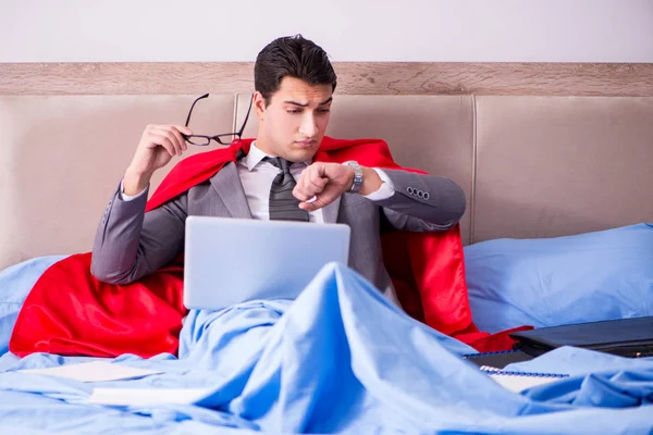 Superhelden-Geschäftsmann arbeitet vom Bett aus — Stockfoto